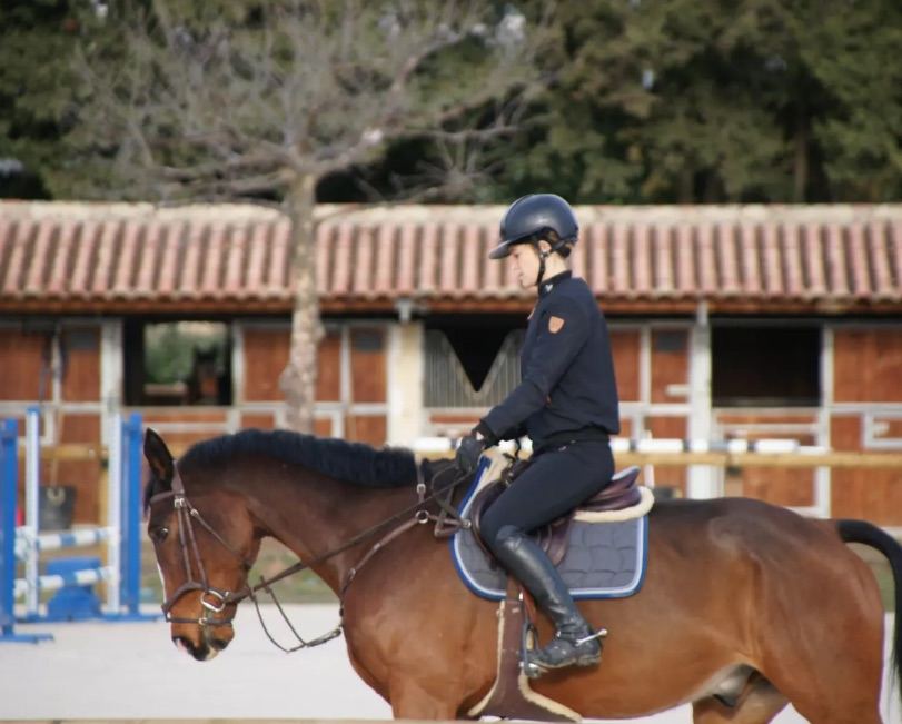 Cavalière au pas devant les écuries